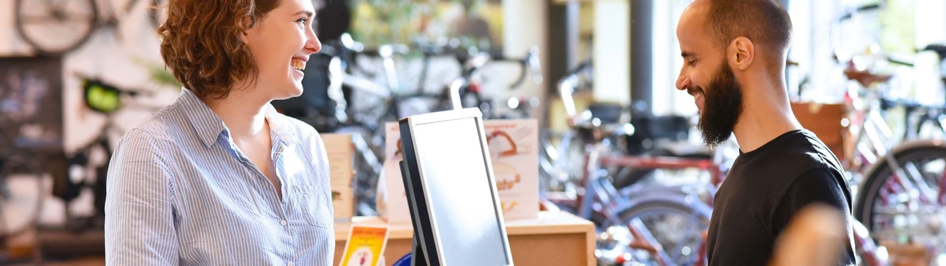 Un vendeur dans une boutique vélo discute à la caisse avec une cliente ravie